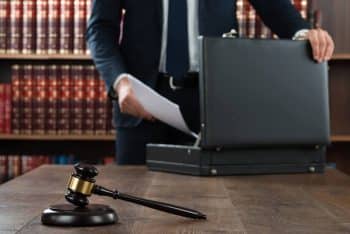 Lawyer putting documents inside their briefcase and a gavel on top of the desk